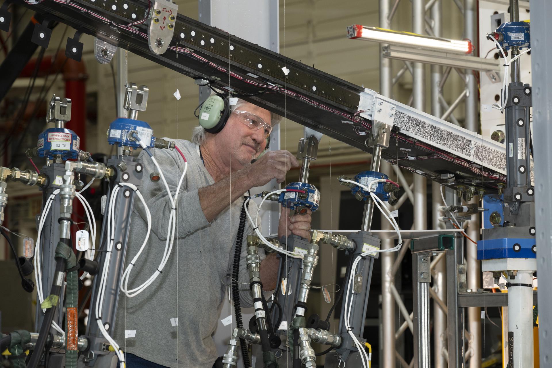 Estructura experimental de una ala sujeta a una bancada de ensayos con sensores y actuadores hidráulicos