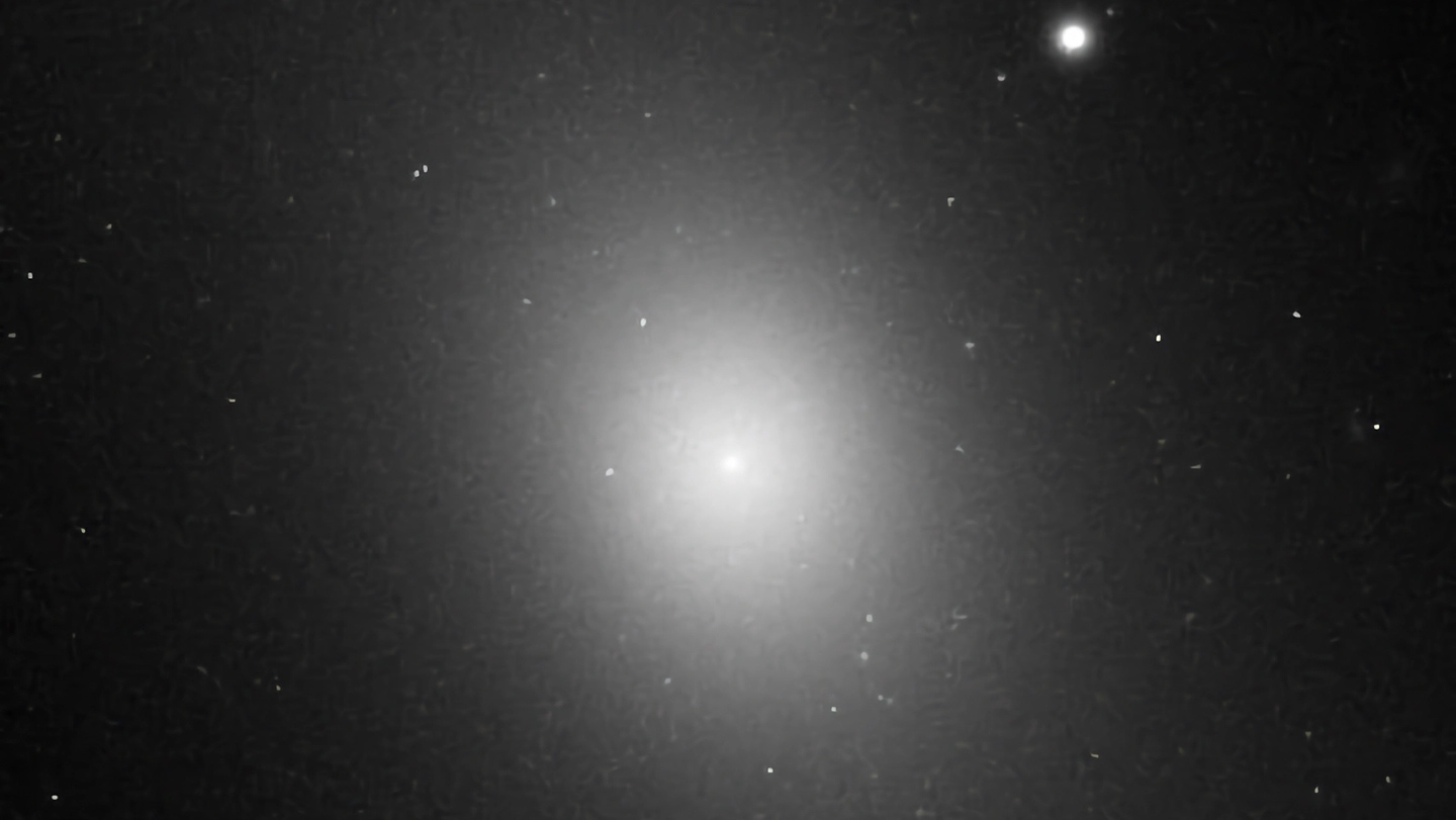 Imagen del telescopio Hubble de la galaxia elíptica IC 1101, visible como una gran mancha luminosa en el centro de un fondo negro espacial