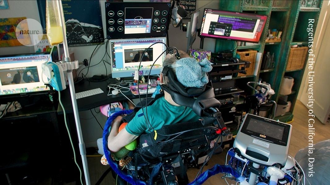 Casey Harrell sentado en su silla de ruedas en su casa mientras usa la interfaz cerebro-computadora, con cables conectados a la cabeza